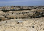 People stand in a cemetery at the Mount of Olives in Jerusalem