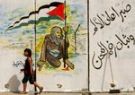 A Palestinian girl walks past a mural at the Rafah border crossing in the southern Gaza Strip